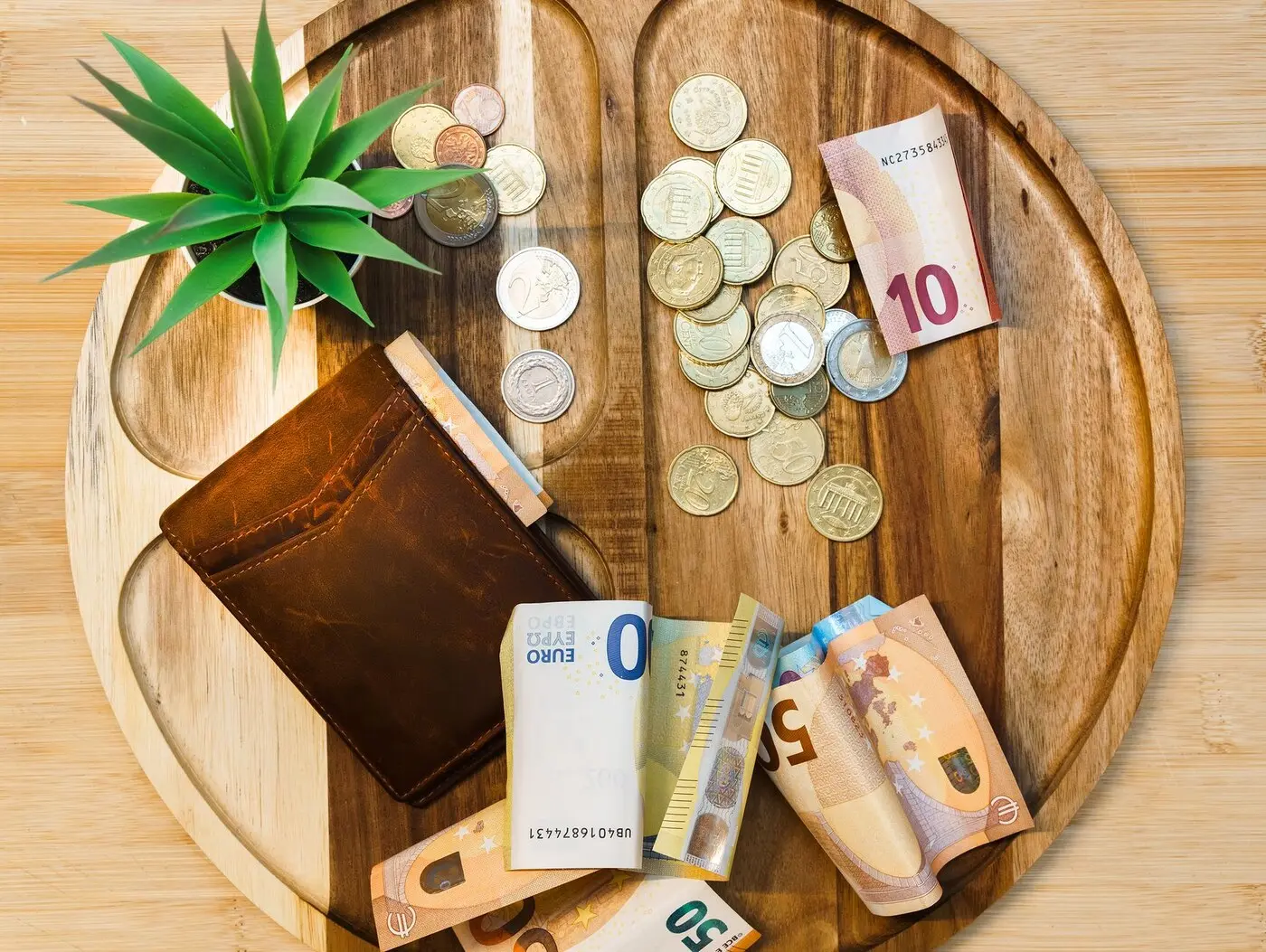 示意图:木盘上的欧元纸币、硬币与钱包(图:Jakub Zerdzicki / Pexels 免费商用许可,图库资料图,非 INPS 相关场景)