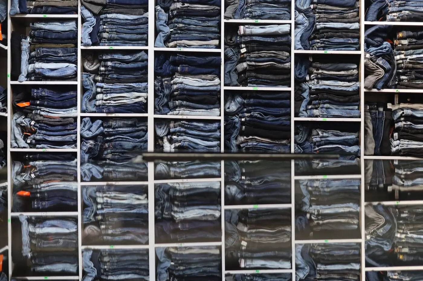 示意图：服装门店货架上分类陈列的牛仔裤（图库资料图，摄影 Saad Bin Hasan / Pexels 免费商用许可）。非普拉托当地门店。